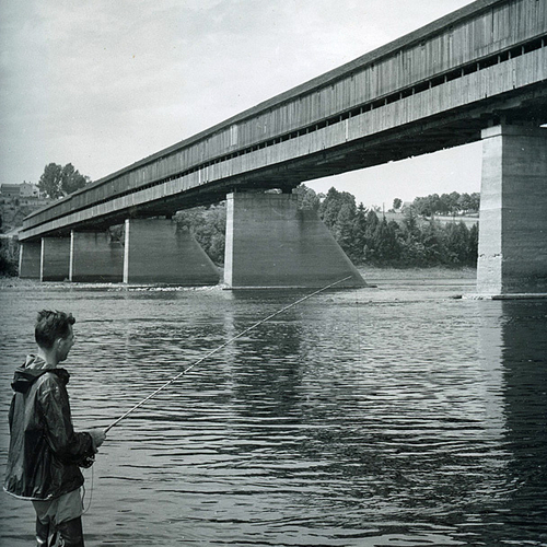 Vintage composition of a sportsman salmon fishing near the Hartland covered bridge in June of 1953.