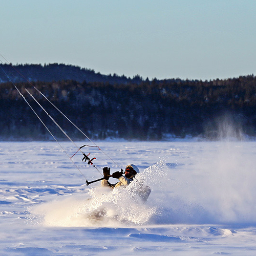 A Snowkiter performs a tacking maneuver and kicks up a bit of snow on a windy day along the Kennebecasis River near R…