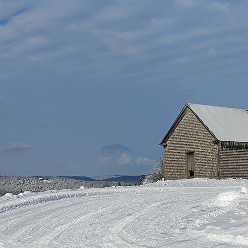An old barn sits along the rise of a hill.