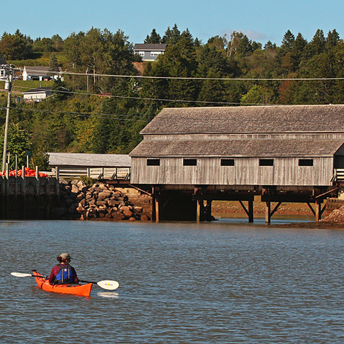 A kayaker gets a seaside view of the historic Irish River #1 covered bridge in picturesque St. Martins, New Brunswick…