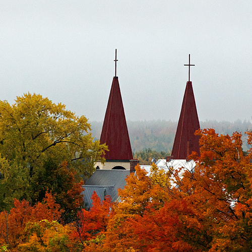 The twin steeples of St. Gertrude's Roman Catholic Church stand tall amongst the colors of the fall season in Woodsto…