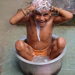 Young boy takes a bath on a footpath Kolkota, India