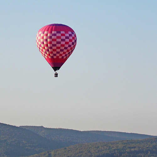 A vibrant hot-air balloon rises above prime farmlands within the bucolic Kennebecasis Valley near Sussex, New Brunswick.