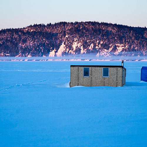 Ice huts along the Kennebecasis amid a backdrop of frigid land fog and an illuminated Minister's Face.