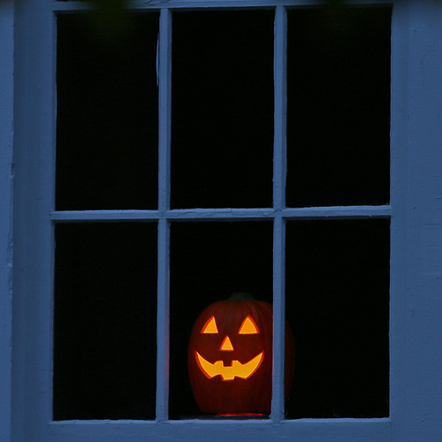 A jack-o-lantern has a front row view on Halloween Eve of the many trick or treaters than will soon be passing within…