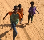 Senegal Fulani three village boys chasing truck  cropped