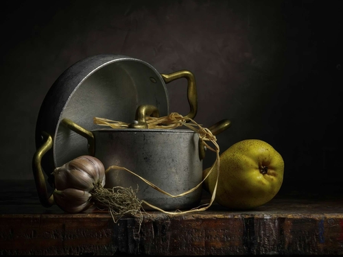 Garlic and Quince. Light-painted still-life photograph of a garlic clove, ripe quince and vintage aluminium kitchenwa…
