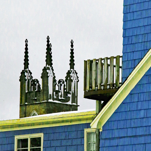 The spires of The Stone Church framed by the corner of a cedar-shingled century home in Uptown Saint John, New Brunsw…