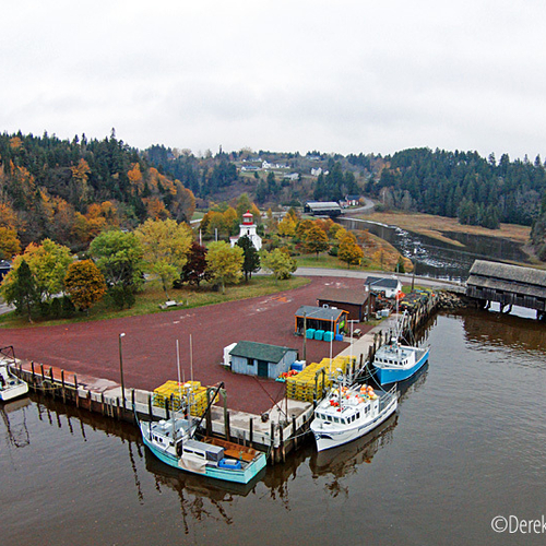 Aerial capture of St. Martins harbor with the near shore fishing vessels, light house & covered bridges in the backgr…