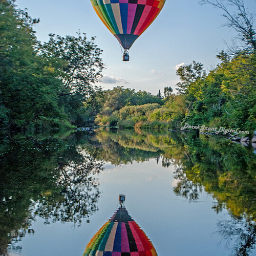 A hot air balloon catches its reflection as it crosses the Kennebecasis River enroute to downtown Sussex.