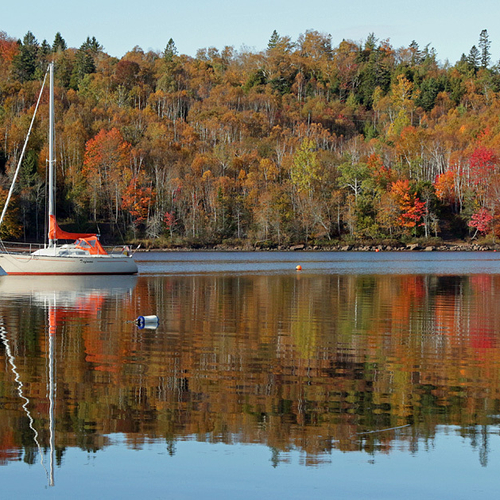 A sailboat moored along the Kennebecasis River amid autumn reflections.