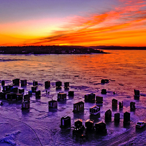 An aerial drone composition of Renforth Ice Fishing Village in Rothesay, New Brunswick at sunset.