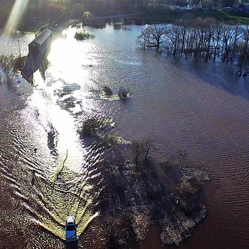 A car runs the road closed barriers and watery gauntlet along Bloomfield Creek Road in rural Kings County New Brunswi…
