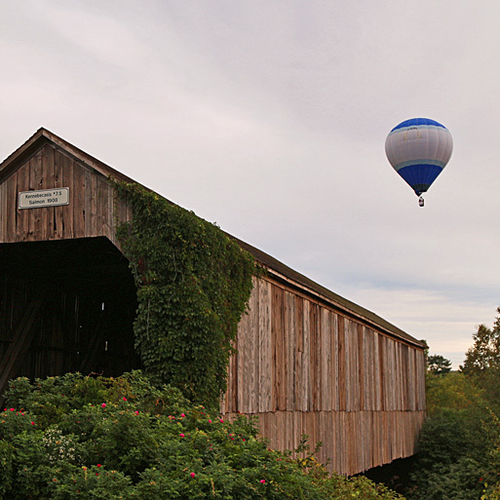 A hot-air balloon passes over the Salmon River Covered Bridge Park near Sussex, New Brunswick. The balloon was partic…