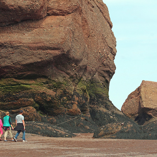 A family tours the giant rock, tide-formed rock formations at Hopewell Cape, New Brunswick.