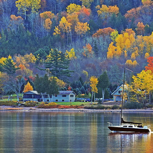 A sailboat passes along Belleisle Bay in rural Kings County, New Brunswick, Canada.