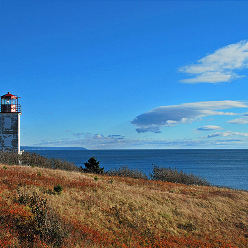 Under an azure blue sky, Quaco Head Lighthouse flashes it's telltale ray of light. Looking eastward and towards Fundy…