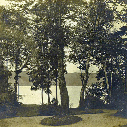 Early view of the Kennebecasis River & Long Island peering through and between two cottages within Rothesay Park in R…