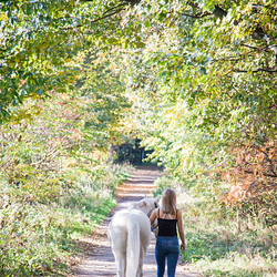 teenage girl walking away with grey pony