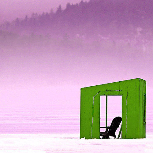 A lawn chair is visible through the opening of a forgotten ice shack along the banks of the foggy Kennebecasis River…