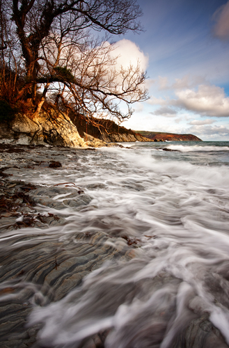 High tide at Garwick Bay as the waves race over the rocky foreshore.