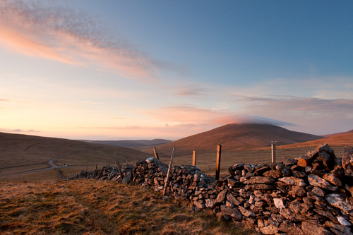 Mist covers the top of Snaefell as the temperature drops to a cool few degrees above zero as the evening sun bathes t…