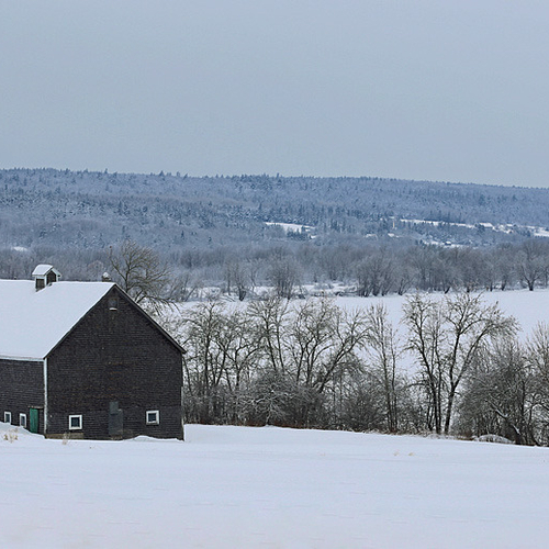 An old barn with a green door overlooks the river valley below.