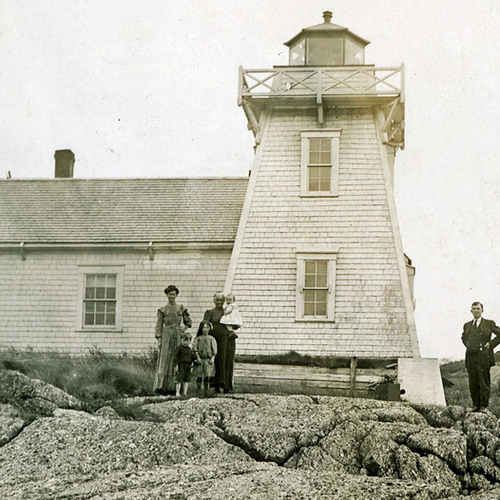An early 20th-century portrait of Pea Point Lighthouse in Blacks Harbor, New Brunswick. Several people can be seen in…