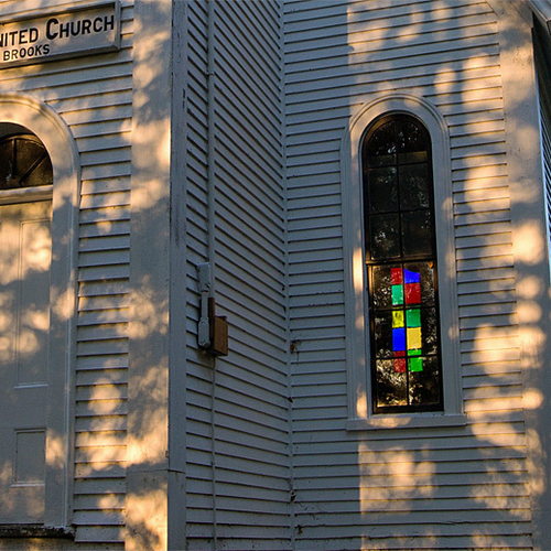 A macro image of St. James United Church in Three Brooks, New Brunswick showing the door and stained glass window.