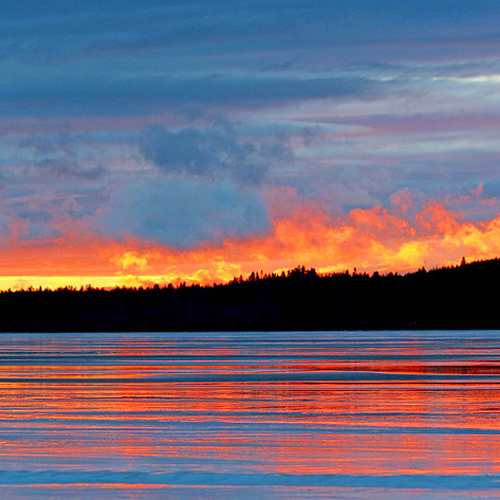 The frozen over Kennebecasis reflects a vibrant winter sunset.