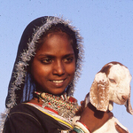 Young smiling girl with baby lamb,India