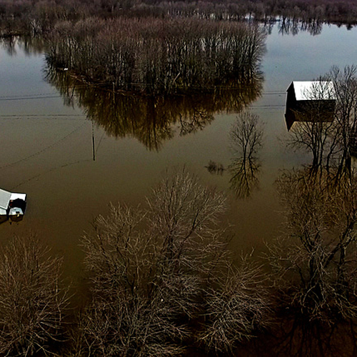 A home and century barn - surrounded by floodwaters in early May 2018 along the banks of the St. John River in New Br…