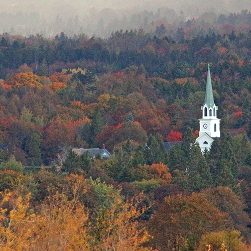 Autumn foliage contrasts with a hail storm and the spire of St. Paul's Anglican church in Rothesay, New Brunswick, Ca…