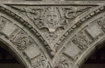 Lower cloister arch, archivolt almohadillado & spandrel relief (sun)