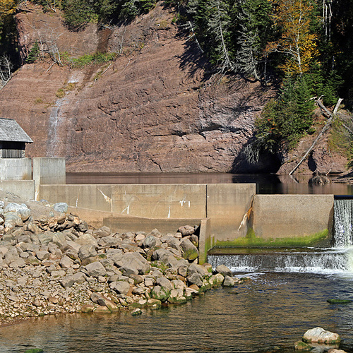 Waterfalls and mill with tide formed rock formations in the background.