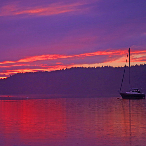 A lone, late summer sailboat becomes enflamed in twilight hues on Kennebecasis Bay in Rothesay, New Brunswick.