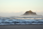 Waves roll in past Goose island on Crantock Beach in Cornwall