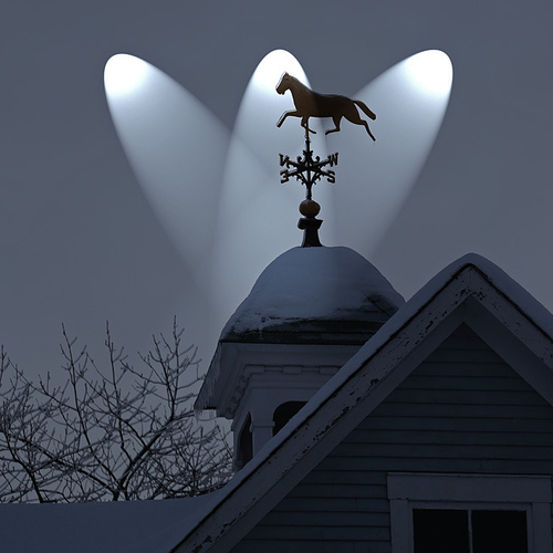 A vintage bronze weathervane silhouetted against winter's drab hues.