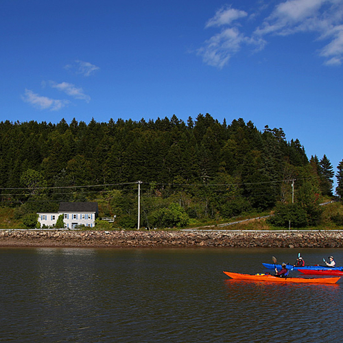 Sea Kayakers enter the Harbour at St. Martins, New Brunswick, Canada.