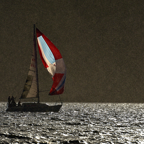 Sunlight breaks through and illuminates the sails of a boat caught in a heavy cloudburst along Kennebecasis Bay near…