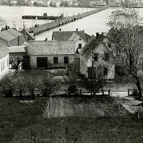 An early 20th century view of Bahurst, New Brunswick, peering through backyards, laundryfilled clothes lines, and loo…