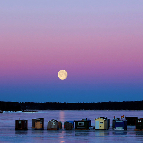 The full wolf moon sets over Kennebecasis bay as a new ice fishing day at Renforth wharf begins.