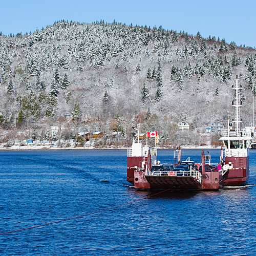 The Gondola Point Ferry is seen crossing the Kennebecasis between Reed's Point and Quispamis amid a snowy mountain ba…