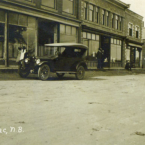Ladies stroll, men wearing top hats, an early automobile, a window sign says "Maritime United". Petitcodiac, NB ~ ci…