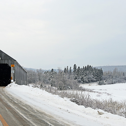 A covered bridge and country church in wintertime.