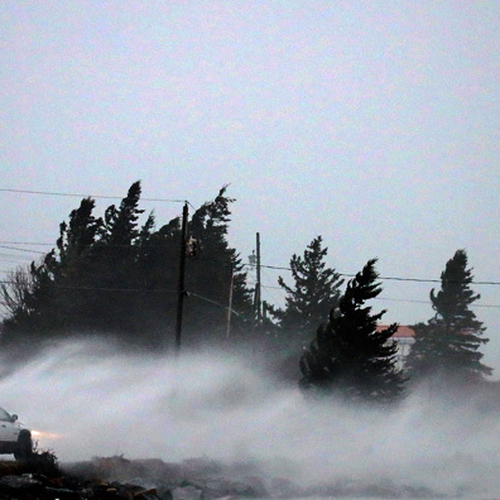Windblown waves and spindrift surges across a road in Charlotte County, New Brunswick at the height of an extreme lat…