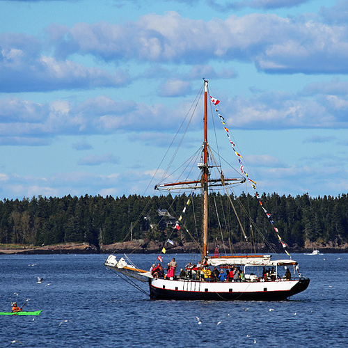 A kayak paddles by a tall ship in Passamaquoddy Bay.