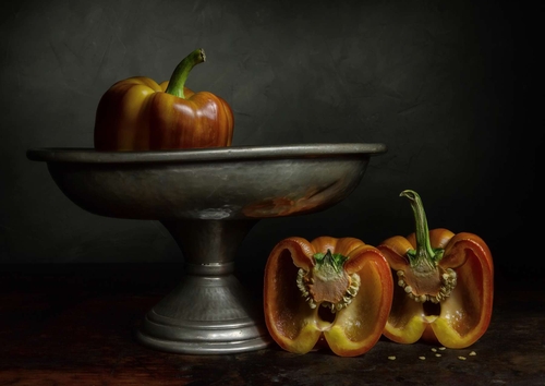 Cut Peppers. Light-painted still-life photograph featuring a pewter dish and two striped peppers, one cut in half. Li…