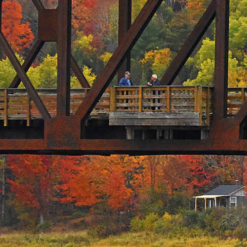 Two gents have a morning chat amid vivid autumn colors along the old Eastern Railway Bridge @Doaktown in Northumberla…