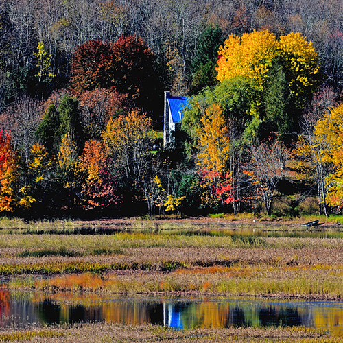 Autumn colors reflect along the Kennebecasis River in Kings County, New Brunswick. Kayaker in the foreground.